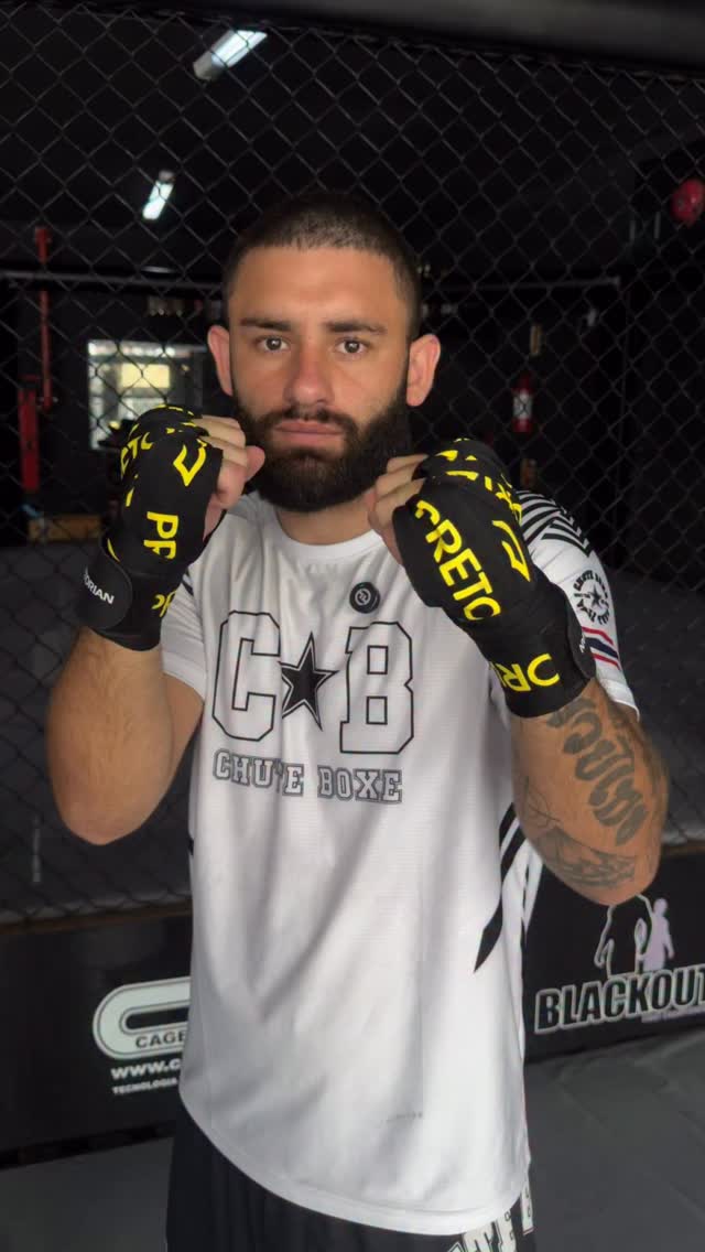Lutador em posição de guarda no cage da academia